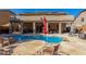Beautiful backyard pool with stone patio, lush landscaping, and covered seating area at 4321 E Morenci Rd, San Tan Valley, AZ 85143