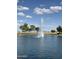 A scenic pond with a central water fountain, bordered by lush green grass and mature trees at 567 E Tropical Dr, Casa Grande, AZ 85122
