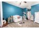 Well-lit bedroom with a turquoise painted wall, white crib, and decor at 5815 E Nora St, Mesa, AZ 85215