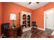 Office room with hardwood floor, an antique desk, a book shelf, and colorful orange walls at 5815 E Nora St, Mesa, AZ 85215