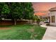 This serene backyard features lush green grass, mature trees, and a tranquil spot for relaxation at 7029 E Monte Cir, Mesa, AZ 85209