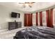 Bedroom with black dresser, flat-screen TV, carpet floors, and plentiful natural light with curtains and shutters at 7029 E Monte Cir, Mesa, AZ 85209