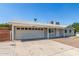 Charming home featuring a spacious driveway and a two-car garage, set beneath a clear blue sky at 7047 W Almeria Rd, Phoenix, AZ 85035