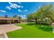 Expansive backyard featuring artificial turf, mature trees, and an outdoor living area at 7102 E Kalil Dr, Scottsdale, AZ 85254