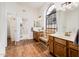 Bathroom featuring double vanity sinks, an arched window, wood-look floors, and an open doorway to the shower at 8977 E Ludlow Dr, Scottsdale, AZ 85260