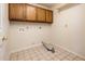 Clean laundry room with tiled floor, oak cabinets, and washer/dryer hookups at 8977 E Ludlow Dr, Scottsdale, AZ 85260