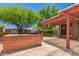 A large brick backyard with a brick barbeque, an outdoor grill, stone pavers, and beautiful green trees at 9603 N 1St Ave, Phoenix, AZ 85021