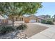 Tan home featuring low maintenance landscaping, a large tree, and a two car garage at 1026 E Julie Ave, San Tan Valley, AZ 85140