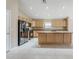 Open kitchen with stainless steel appliances, light wood cabinets, and tiled flooring at 1026 E Julie Ave, San Tan Valley, AZ 85140