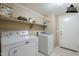 Well-lit laundry room with a washer, dryer, and storage shelves at 1026 E Julie Ave, San Tan Valley, AZ 85140