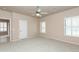 This bedroom features neutral walls, carpet flooring, large windows with shutters, and a ceiling fan at 11419 E Ellis St, Mesa, AZ 85207