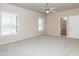 Main bedroom with carpet, ceiling fan, and two windows with plantation shutters at 11419 E Ellis St, Mesa, AZ 85207