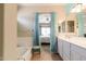 Bright bathroom showcasing tub with blue curtains leading to Primary bedroom and white double sink vanity at 1461 W Brangus Way, San Tan Valley, AZ 85143