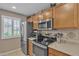 Well-equipped kitchen with stainless steel appliances, wood cabinets, and ample counter space at 15470 W Mauna Loa Ln, Surprise, AZ 85379