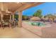 Spacious backyard with a covered patio and lounge chairs overlooking a sparkling pool and manicured landscaping at 16375 W Cortez St, Surprise, AZ 85388