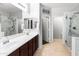 Bright bathroom featuring dual sinks, a sleek mirror, and a glass-enclosed shower at 16375 W Cortez St, Surprise, AZ 85388