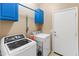 This laundry room features a matching washer and dryer, bright blue cabinets and tile flooring at 16375 W Cortez St, Surprise, AZ 85388
