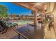 Relaxing covered patio with ceiling fans, a ping pong table, and a view of the sparkling pool at 16375 W Cortez St, Surprise, AZ 85388