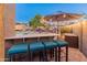 Outdoor bar area with seating overlooking a sparkling pool and a beautifully landscaped backyard at 16375 W Cortez St, Surprise, AZ 85388