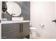 Modern bathroom features a round mirror, vessel sink, and sleek vanity with dark wood finish and black fixtures at 16772 W Cypress St, Goodyear, AZ 85395