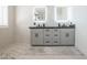 Bright bathroom featuring a double vanity with lighted mirrors and neutral tile floors at 16772 W Cypress St, Goodyear, AZ 85395