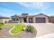 Charming stone and stucco home with a manicured lawn, paved driveway, and a two-car garage at 16772 W Cypress St, Goodyear, AZ 85395