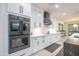 Kitchen showcasing stainless double oven, white cabinetry, and a black vent hood at 16772 W Cypress St, Goodyear, AZ 85395