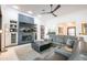 Bright living room with ceiling fan, fireplace with built-in shelving, and gray sectional sofa at 16772 W Cypress St, Goodyear, AZ 85395