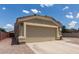 Side view of a tan home showing the 2-car garage and spacious driveway on a sunny day, surrounded by gravel at 1680 E Cardinal Dr, Casa Grande, AZ 85122