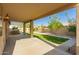 Covered patio with view of backyard featuring green turf, mature trees, and desert landscaping at 2183 W Hawken Way, Chandler, AZ 85286