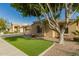 Home featuring desert landscaping, green grass, and a large shade tree on a sunny day at 2183 W Hawken Way, Chandler, AZ 85286