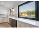 Modern kitchen featuring white cabinetry, stainless steel appliances, and a large window with views of the backyard pool at 24433 N 75Th St, Scottsdale, AZ 85255