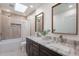 Well-lit bathroom featuring double sinks, granite countertop, skylight, and shower with tub at 2724 W Colt Rd, Chandler, AZ 85224