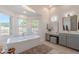 Bright bathroom featuring a soaking tub, double windows, and gray vanity with decorative fixtures at 2724 W Colt Rd, Chandler, AZ 85224