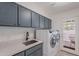 Convenient laundry room featuring grey cabinets, white counters, sink, and modern washer/dryer at 2724 W Colt Rd, Chandler, AZ 85224