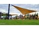 Community playground featuring a shade sail, climbing structures, a slide, and lush green lawn area for play and recreation at 35017 N Sacramento Wash Rd, San Tan Valley, AZ 85144