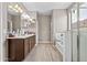 Well-lit bathroom with double sinks, a shower, and a tub and wood-look flooring at 3529 N Brooklyn Dr, Buckeye, AZ 85396