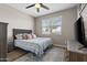 Cozy bedroom featuring a tufted headboard bed, wood-look floors, a ceiling fan and natural light from the window at 3529 N Brooklyn Dr, Buckeye, AZ 85396