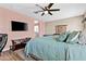 Relaxing main bedroom featuring a ceiling fan and a mounted TV and wood-look flooring at 3529 N Brooklyn Dr, Buckeye, AZ 85396