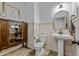 Stylish half bathroom featuring decorative mirror and cabinet with a pedestal sink at 40445 W Bravo Dr, Maricopa, AZ 85138