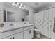 Bright and modern bathroom featuring double sinks, white cabinetry, and a shower with a shower curtain at 40445 W Bravo Dr, Maricopa, AZ 85138