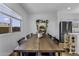 Bright dining area with natural light, an elegant wooden table, and a decorative plant shelf at 40445 W Bravo Dr, Maricopa, AZ 85138