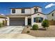 Inviting two-story home with a gray garage door, tile roof, and low-maintenance desert landscaping at 40445 W Bravo Dr, Maricopa, AZ 85138