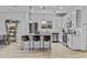 Open kitchen with stainless appliances, island seating, modern pendant lighting, and light wood tile flooring at 40445 W Bravo Dr, Maricopa, AZ 85138