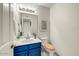 Updated powder room with blue vanity, wood toilet seat and neutral wall art at 5710 E Anderson Dr, Scottsdale, AZ 85254