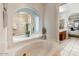 Elegant bathroom featuring a soaking tub with arched mirror and entry to bedroom at 5710 E Anderson Dr, Scottsdale, AZ 85254