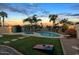 Inviting backyard oasis featuring a sparkling pool, lush lawn, and mature palm trees at 7140 E Juanita Ave, Mesa, AZ 85209