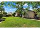 Well-manicured backyard with mature trees, a covered patio, and a lush lawn at 7925 E Osage Ave, Mesa, AZ 85212
