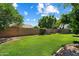 Spacious backyard with lush lawn, mature trees, and secure privacy fence, perfect for outdoor enjoyment at 7925 E Osage Ave, Mesa, AZ 85212