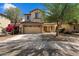 Two-story home with tan stucco, two-car garage, desert landscaping, covered porch and blooming shrub at 973 E Corral St, Avondale, AZ 85323